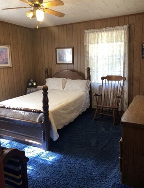 Cozy retreat with a bed, rocking chair, and nightstand, set against a traditional backdrop.