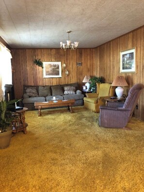 Relax in this inviting living room with a comfortable sofa set, chandelier, and cozy touches.