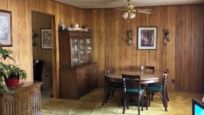 A dining area with a wooden table and chairs, a cabinet, and a ceiling fan.
