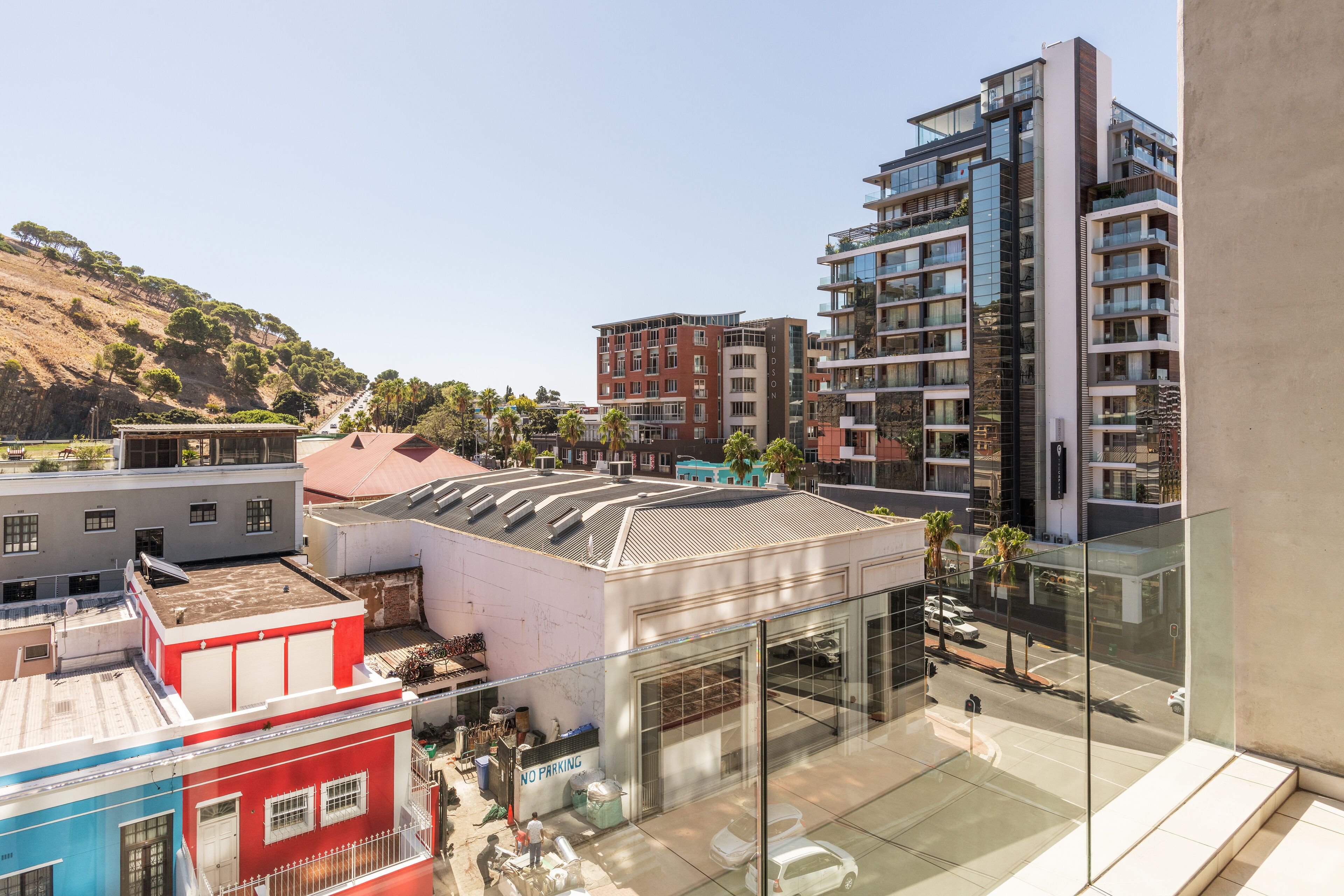 En moderne bygning med en glasfacade, parkeringsplads og udsigt over et bakket landskab.