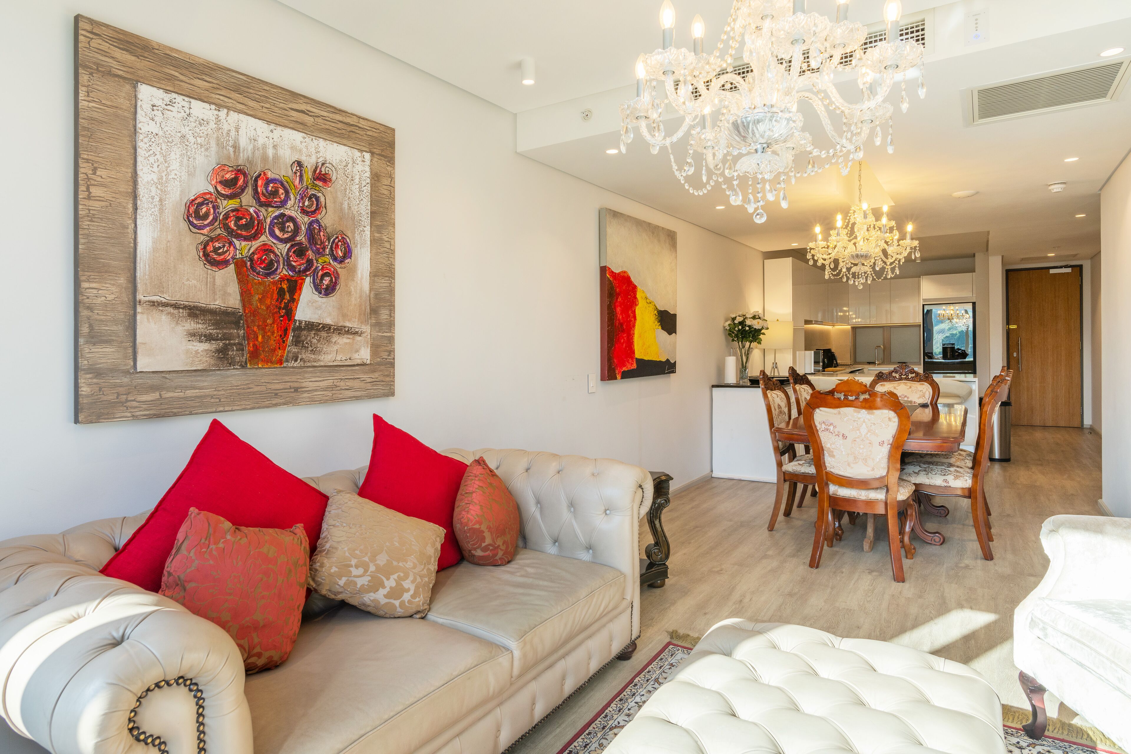 A modern living room with a sofa, a dining area, and a kitchen in the background.