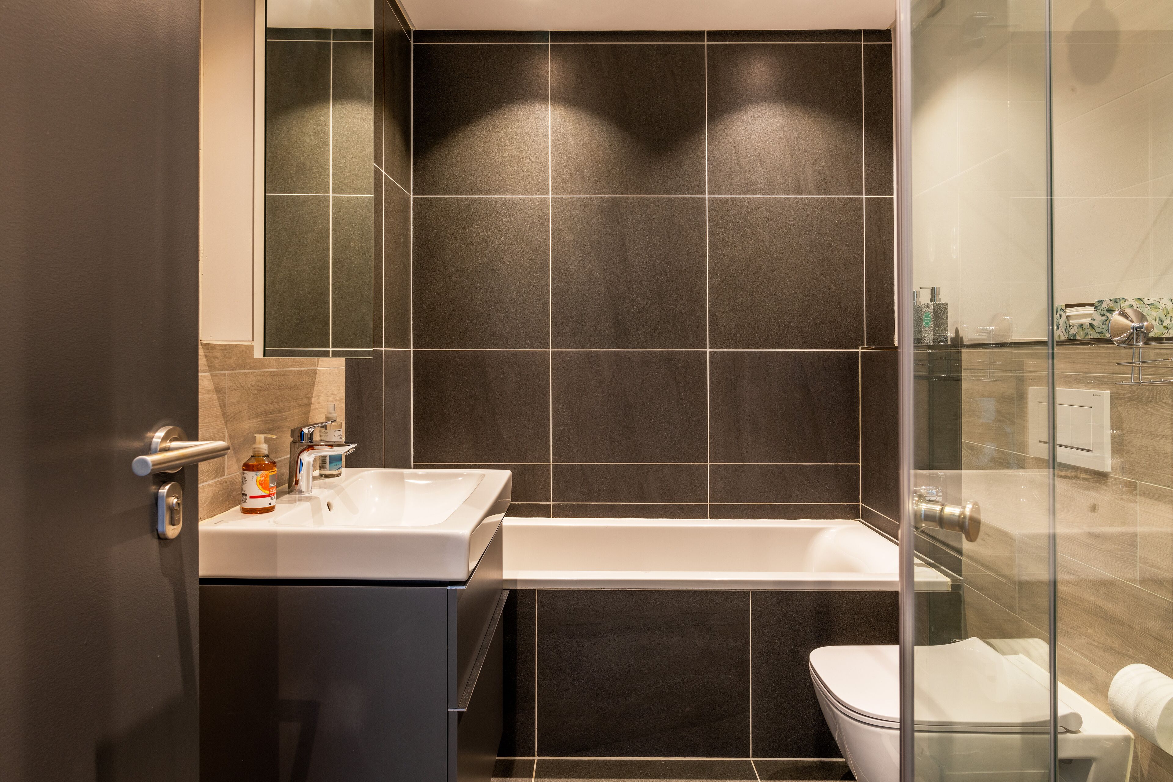 Een moderne badkamer met een groot bad, een toilet en een wastafel.