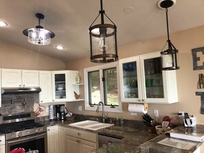A kitchen with white cabinets, a granite countertop, stainless steel appliances, and pendant lighting.