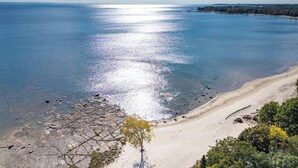 Een kustlandschap met heldere lucht, een zandstrand en een rotsachtige kustlijn.