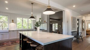 Een ruime keuken met een groot eiland, hangende verlichting en uitzicht op de omgeving.