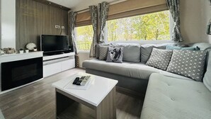 Un espacio habitable pequeño con televisor, sofá y una mesita de centro.