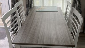 Un comedor con una mesa y sillas, una ventana con cortinas y vistas al exterior.