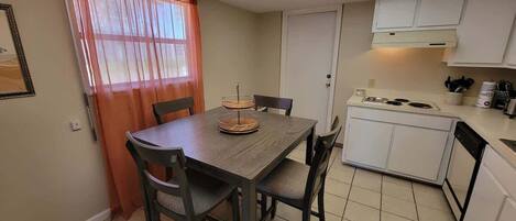 A compact kitchen with a dining table, chairs, a stove, and cabinets.