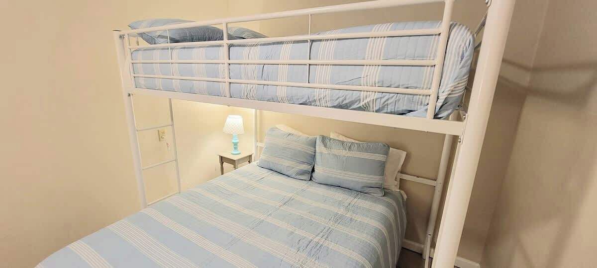 A bunk bed with a lower bed and a higher bunk, both with striped bedding.