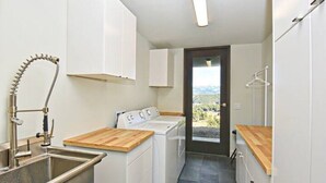 A compact laundry room with a washing machine, a sink, and a wooden countertop. - Berghaus Pagosa - Experience the Alpenglow (Pagosa Springs)
