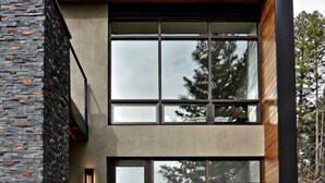 A modern two-story building with large windows, a stone facade, and outdoor seating. - Berghaus Pagosa - Experience the Alpenglow (Pagosa Springs)