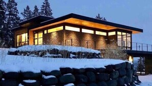 A modern house with a stone foundation, large windows, and a warm interior light. - Berghaus Pagosa - Experience the Alpenglow (Pagosa Springs)