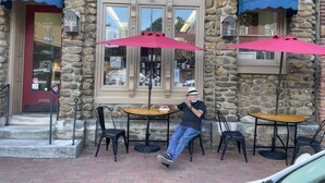 A stone building with a red door, two blue awnings, and a window with a sign. - Historic House in Downtown Waynesville! With a firepit!  And Hot Tub 😄 (Waynesville)