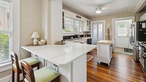 A modern kitchen with a central island, wooden chairs, a dining table, and a refrigerator. - Historic House in Downtown Waynesville! With a firepit!  And Hot Tub 😄 (Waynesville)