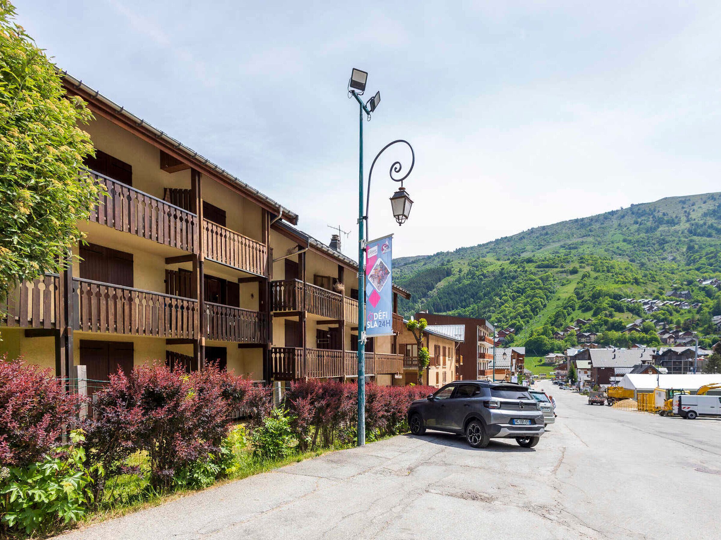 Ein mehrstöckiges Hotel mit Balkonen, eine Straße davor und eine gebirgige Kulisse.