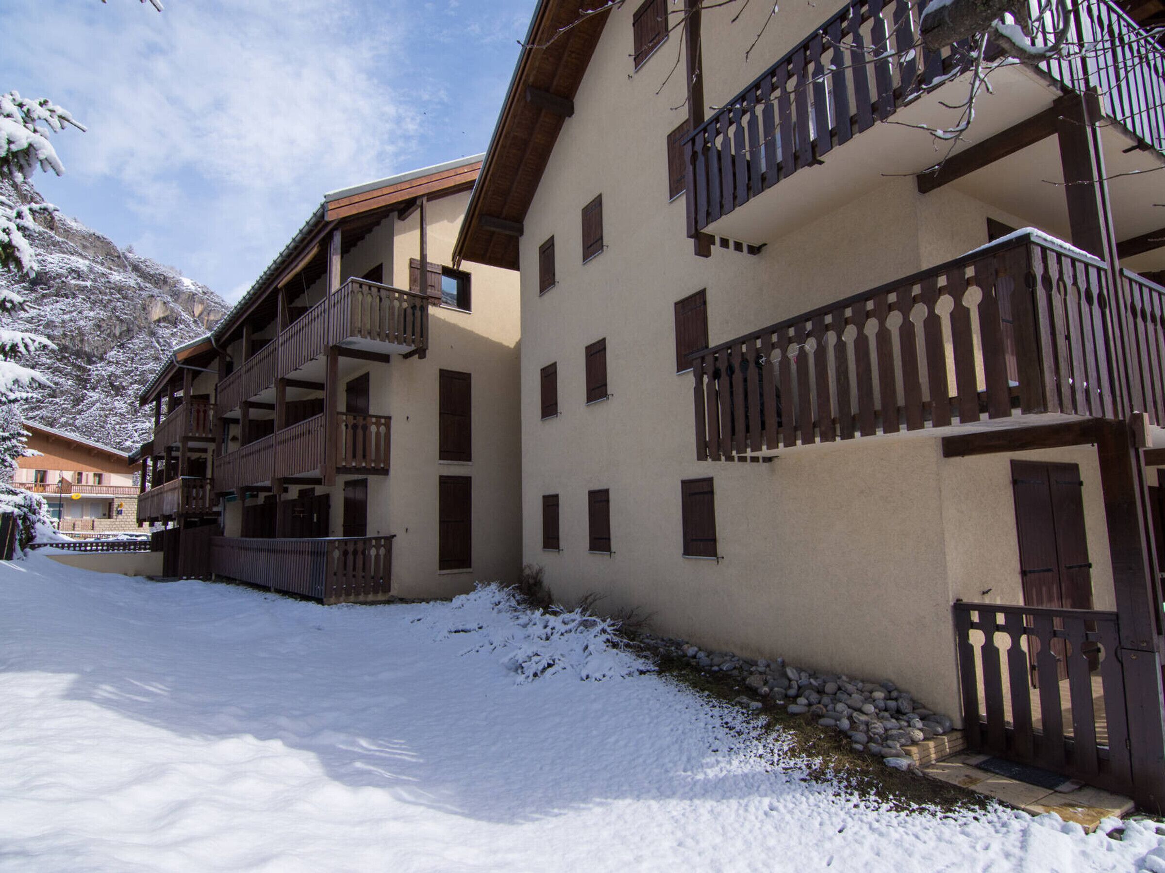 A snow-covered courtyard with multi-story buildings featuring balconies and wooden railings.