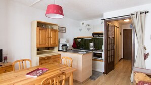 A compact kitchen with wooden cabinets, a dining table, and a red pendant light. - Studio cabin 4 ppl, parking, wifi (Valloire)