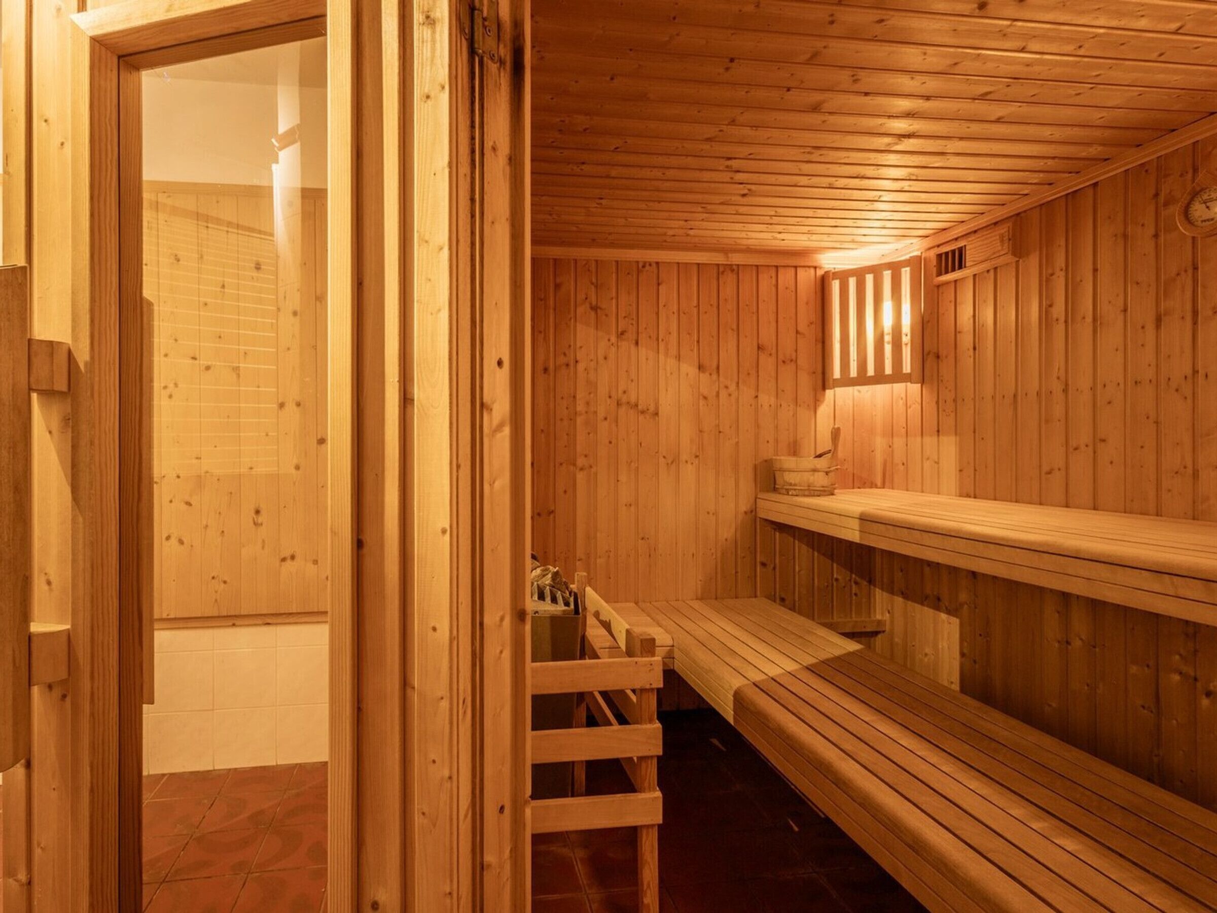 Eine Holzsauna mit Bänken, darunter eine Bank mit Rückenlehne.