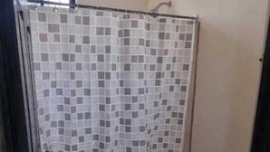 Ein kleines Badezimmer mit gefliestem Duschbereich, Toilette und Waschbecken.