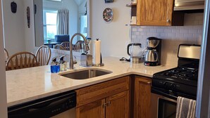 A modern kitchen with wooden cabinets, a stainless steel sink, a coffee maker, and a dishwasher. - Ski In/Ski Out Winterplace 2BR+Loft W/Fireplace, Hot Tub and Pool Access (Ludlow)