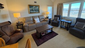 A cozy living room with a sofa, armchairs, a coffee table, and a painting on the wall. - Ski In/Ski Out Winterplace 2BR+Loft W/Fireplace, Hot Tub and Pool Access (Ludlow)