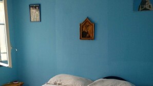 A bedroom with a bed, pillows, a wooden nightstand, and a small table. - Beautiful 4-bed Villa in Noto (Noto)