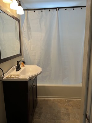 Bañera con ducha, toallas, jabón, papel higiénico
