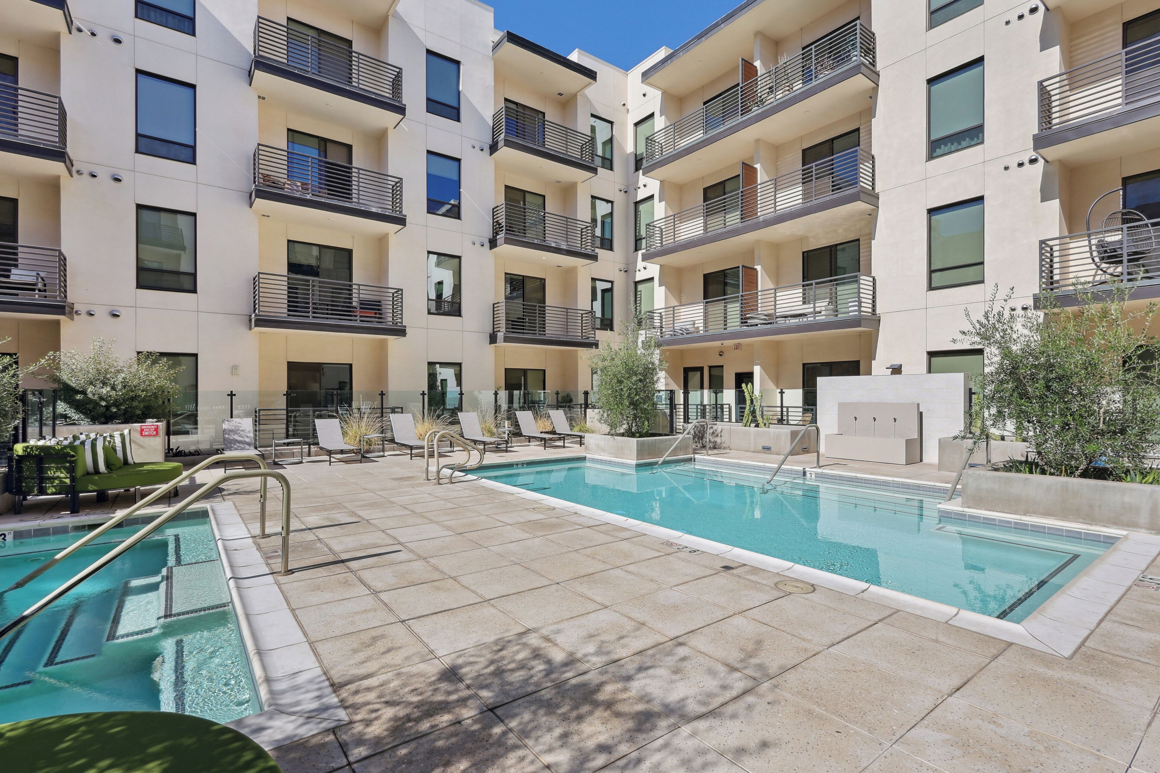 Un immeuble d’appartements moderne doté d’une piscine, d’un espace extérieur aménagé et de balcons.