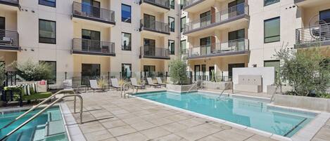 Un immeuble d’appartements moderne doté d’une piscine, d’un espace extérieur aménagé et de balcons.