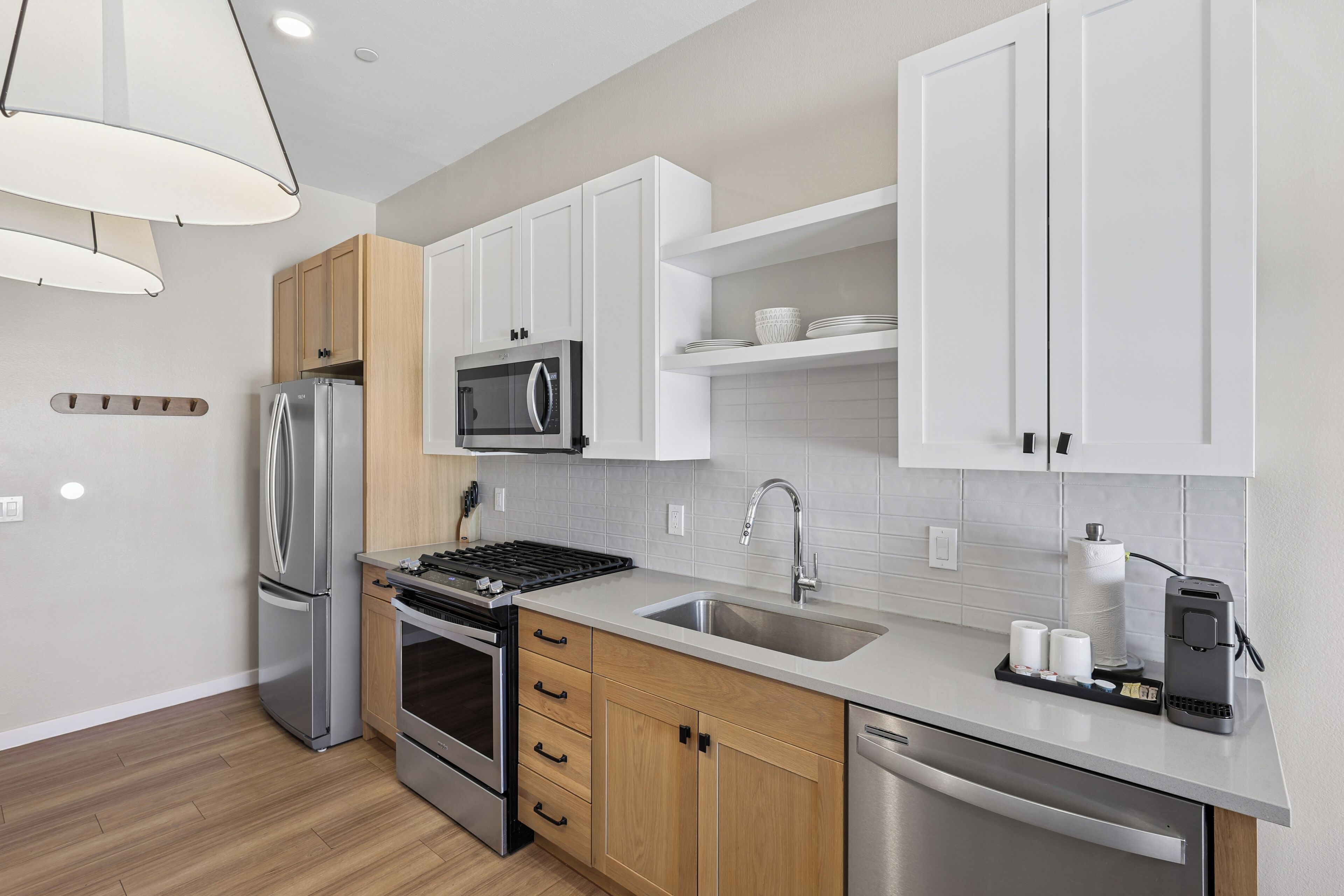 A modern kitchen with stainless steel appliances, wooden cabinets, and a grey countertop.