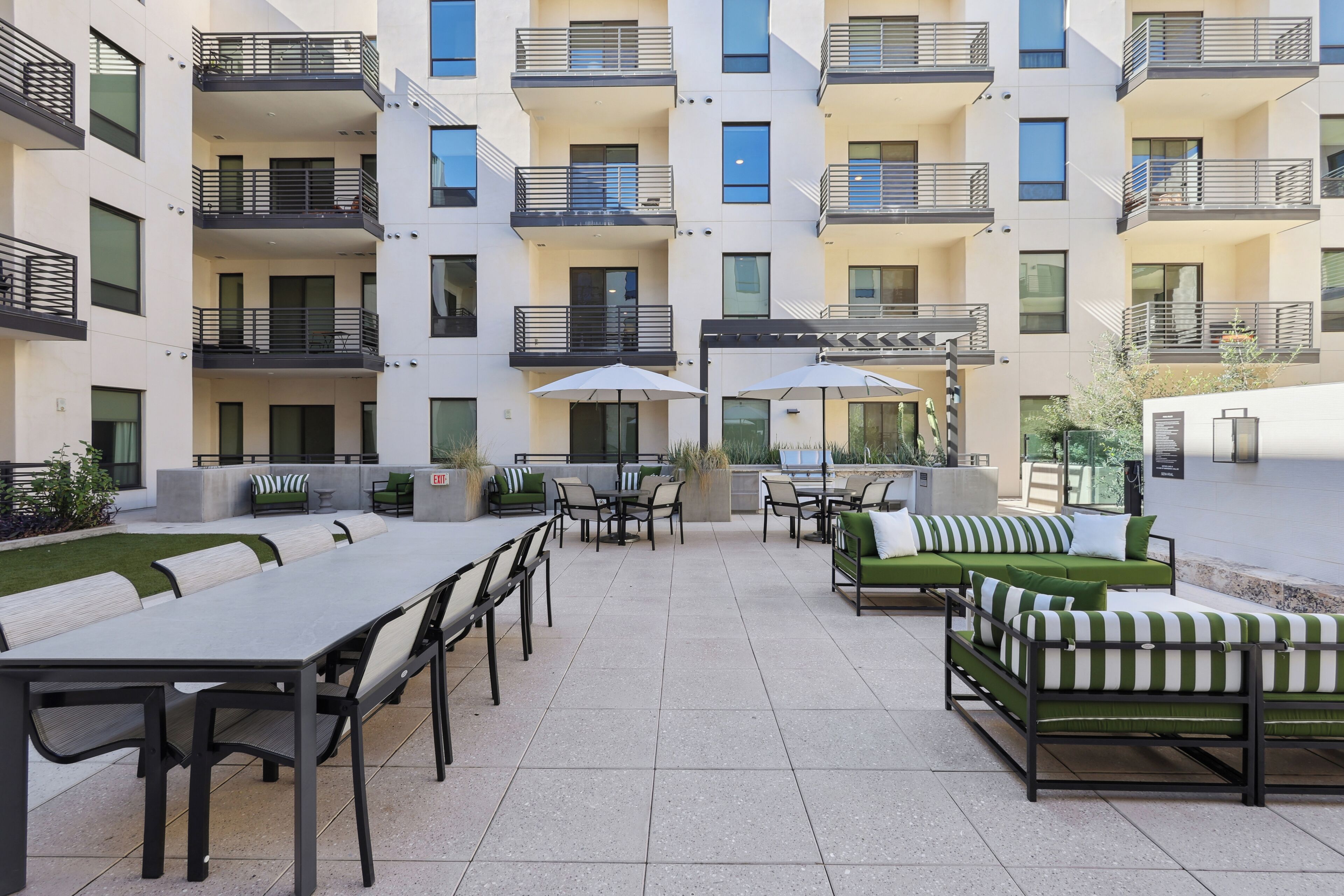 A multi-story residential building with balconies, outdoor seating areas, and a tiled patio.
