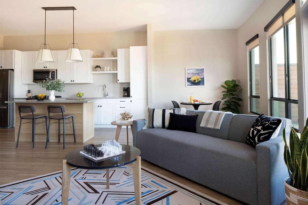 A modern living room with a grey sofa, a coffee table, and a patterned rug.