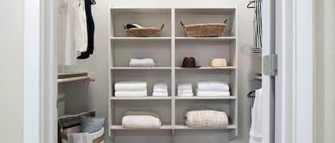 Un armario vestidor con estantes y cestas para guardado, una barra para colgar ropa y suelo cubierto de moqueta.