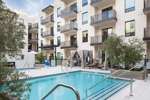 Una piscina al aire libre, sombrillas, sillones reclinables de piscina