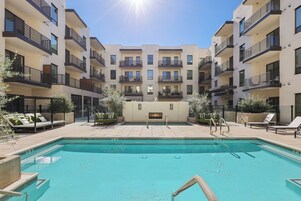 Una piscina al aire libre, sombrillas, sillones reclinables de piscina