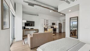 Eine moderne Wohnung mit einem großen Bett, einer Couch, einer Küche und einem Essbereich.