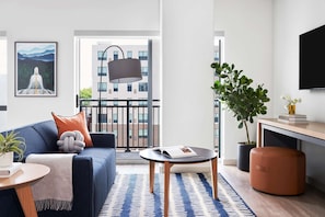 Relax in this stylish living space with a comfortable sofa, coffee table, and side table, offering a view of the surrounding buildings.