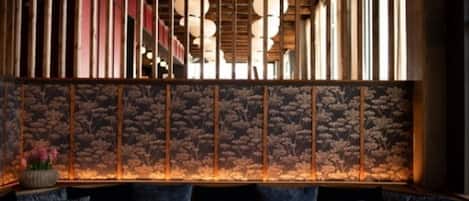 A restaurant interior with a wooden partition, round tables, and a patterned wall.