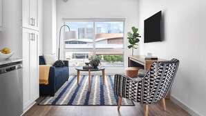 Ein modernes Wohnzimmer mit einer Couch, einem gemusterten Sessel, einem Couchtisch und einem an der Wand montierten Fernseher.
