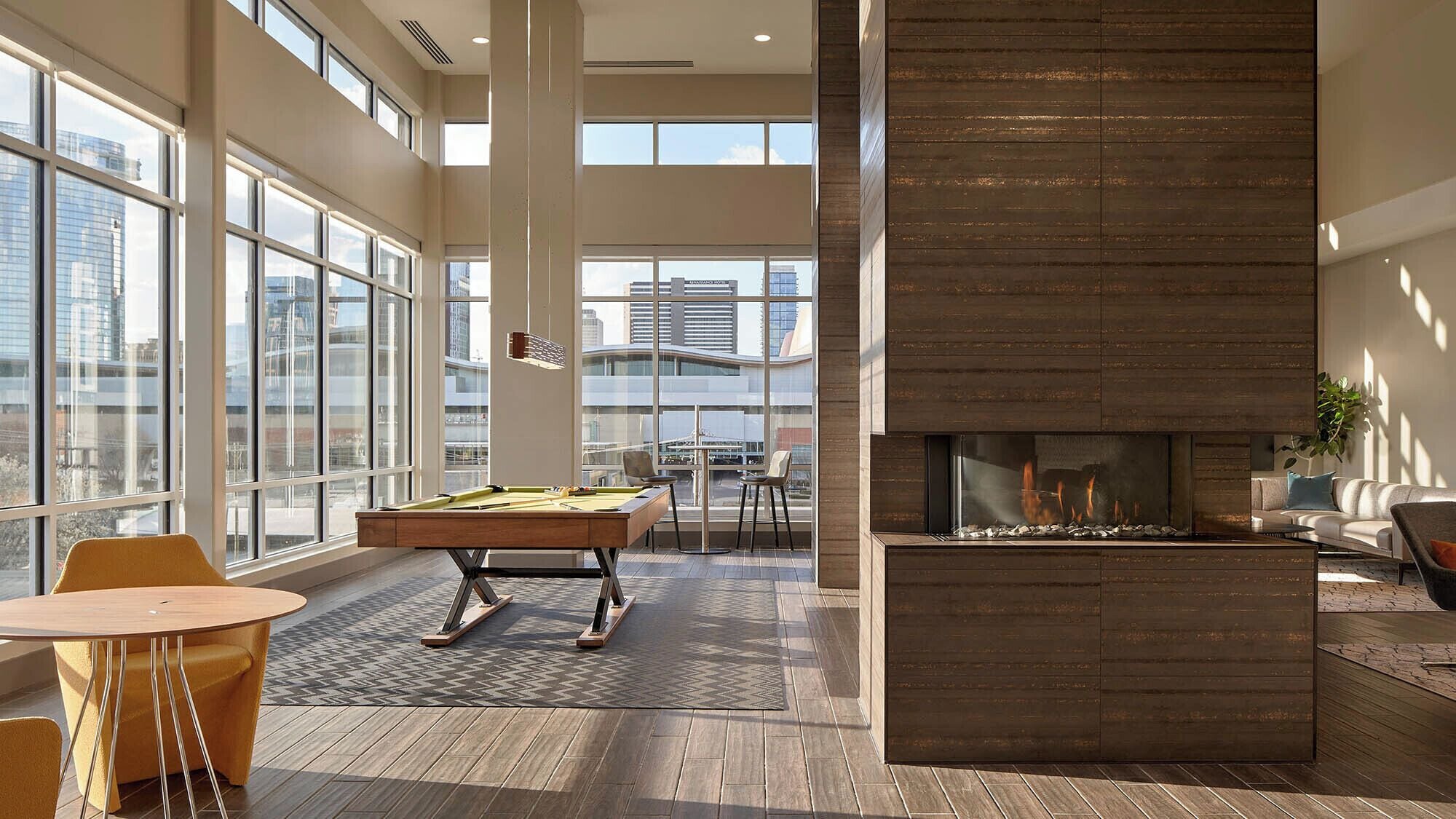 A modern lounge area with a pool table, comfortable seating, and a fireplace.