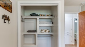 Un dressing accessible sans porte, doté d’étagères ouvertes, d’une tringle et d’un plancher en bois.