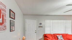 Un salon avec un canapé rouge, un plaid en crochet et des tableaux encadrés accrochés au mur.