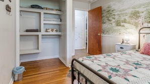 Une chambre à coucher comprenant un lit, une table de chevet, une lampe, une décoration murale et une armoire avec des étagères.