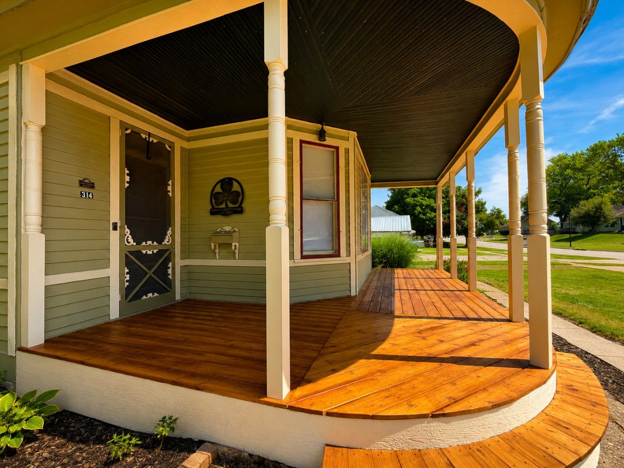 A covered porch with a wooden deck, a door with a decorative glass panel, and a small bench.