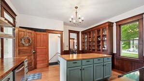 A spacious kitchen with wooden cabinets, a central island, and a chandelier.