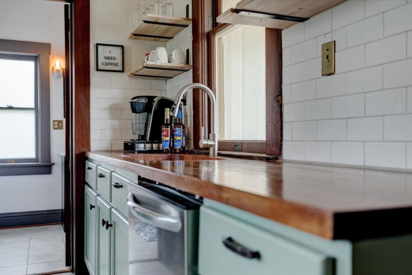 A kitchen with a coffee machine, a sink, and a window.