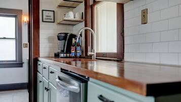 A kitchen with a coffee machine, a sink, and a window.