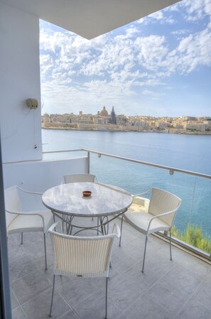 A balcony with a table and chairs, overlooking a body of water and a cityscape. - Spacious apartment with breathtaking views GOSLM5 (Sliema)