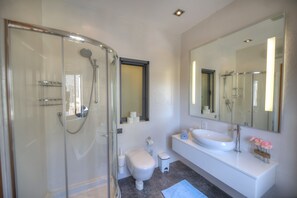 A modern bathroom with a glass-enclosed shower, a white sink, and a large mirror. - Spacious apartment with breathtaking views GOSLM5 (Sliema)