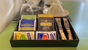 Una caja de productos de té y café, incluyendo marcas como Sognidor, TWININGS y Nescafe Gold.